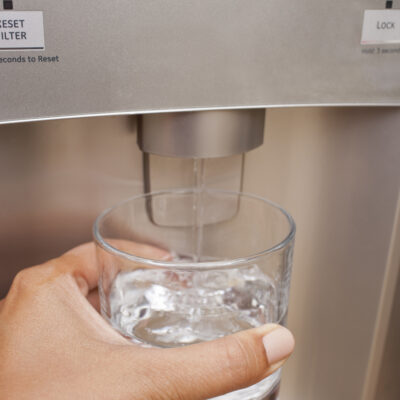 Woman getting herself a glass of filtered water from the refrigerator