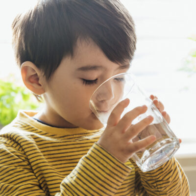 Close up of a young boy drinking from a glass of water